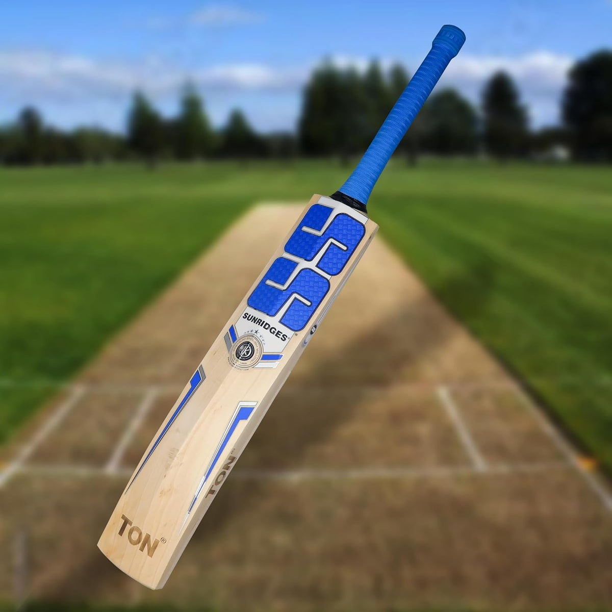 SS Custom English Willow cricket bat displayed on a cricket field, showcasing its fine grain structure and ergonomic handle.